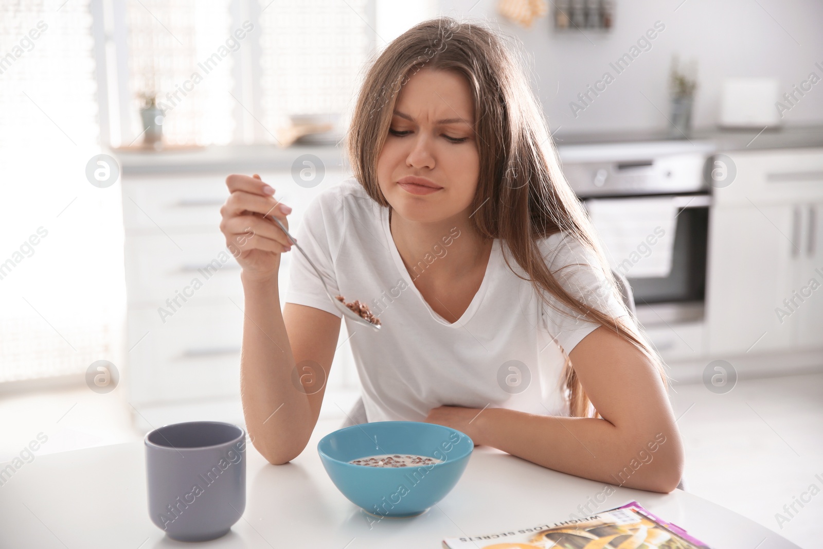 Photo of Sleepy young woman eating breakfast at home in morning