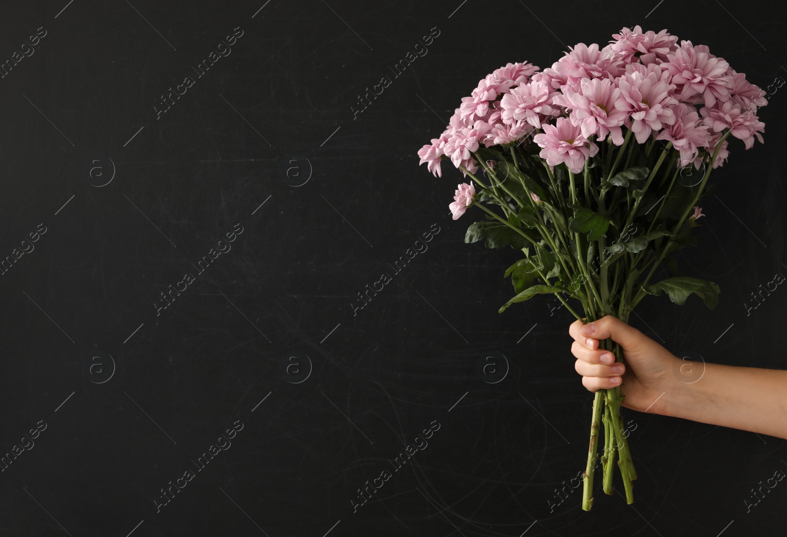 Photo of Woman holding beautiful bouquet near black chalkboard, space for text. Happy Teacher's Day