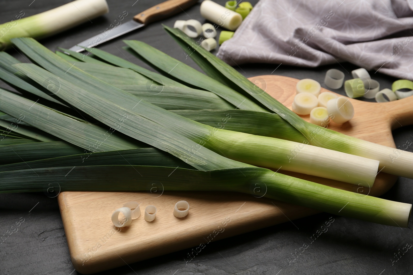 Photo of Fresh raw leeks on black table, closeup