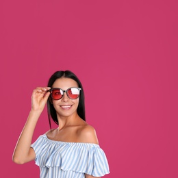 Beautiful woman wearing sunglasses on pink background. Space for text