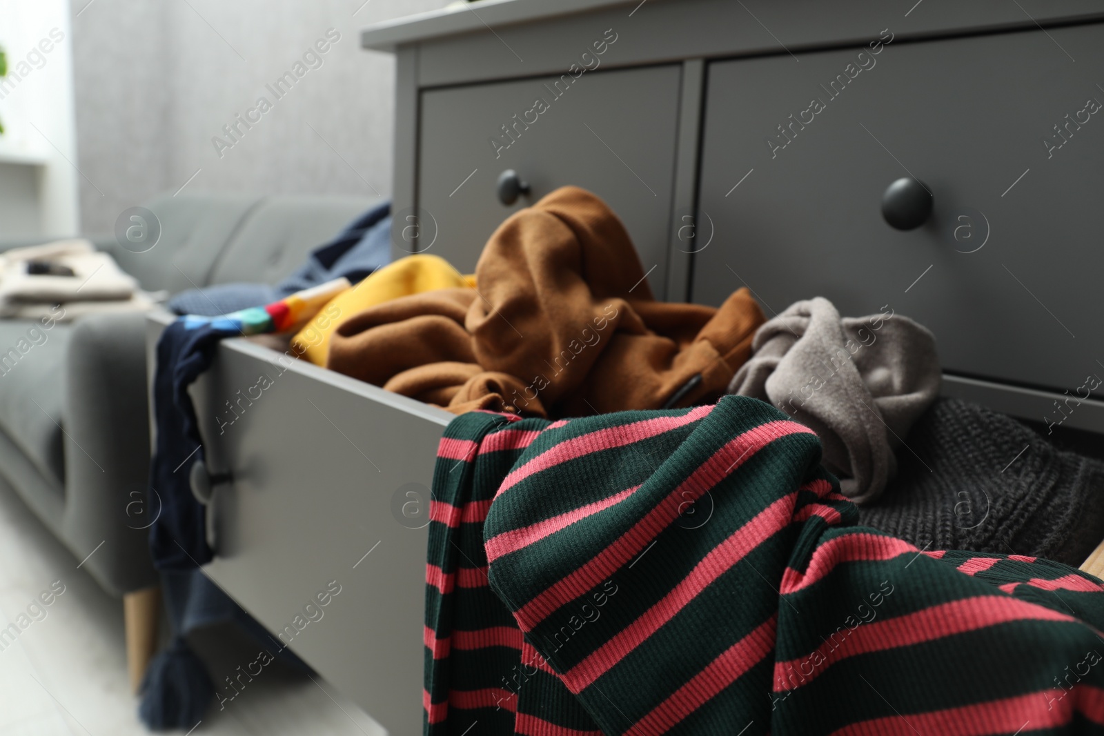 Photo of Cluttered chest of drawers indoors, closeup. Clothes in mess