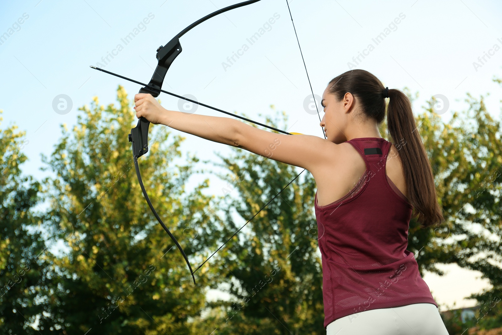 Photo of Woman with bow and arrow practicing archery outdoors