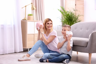 Photo of Mother and son with piggy banks at home