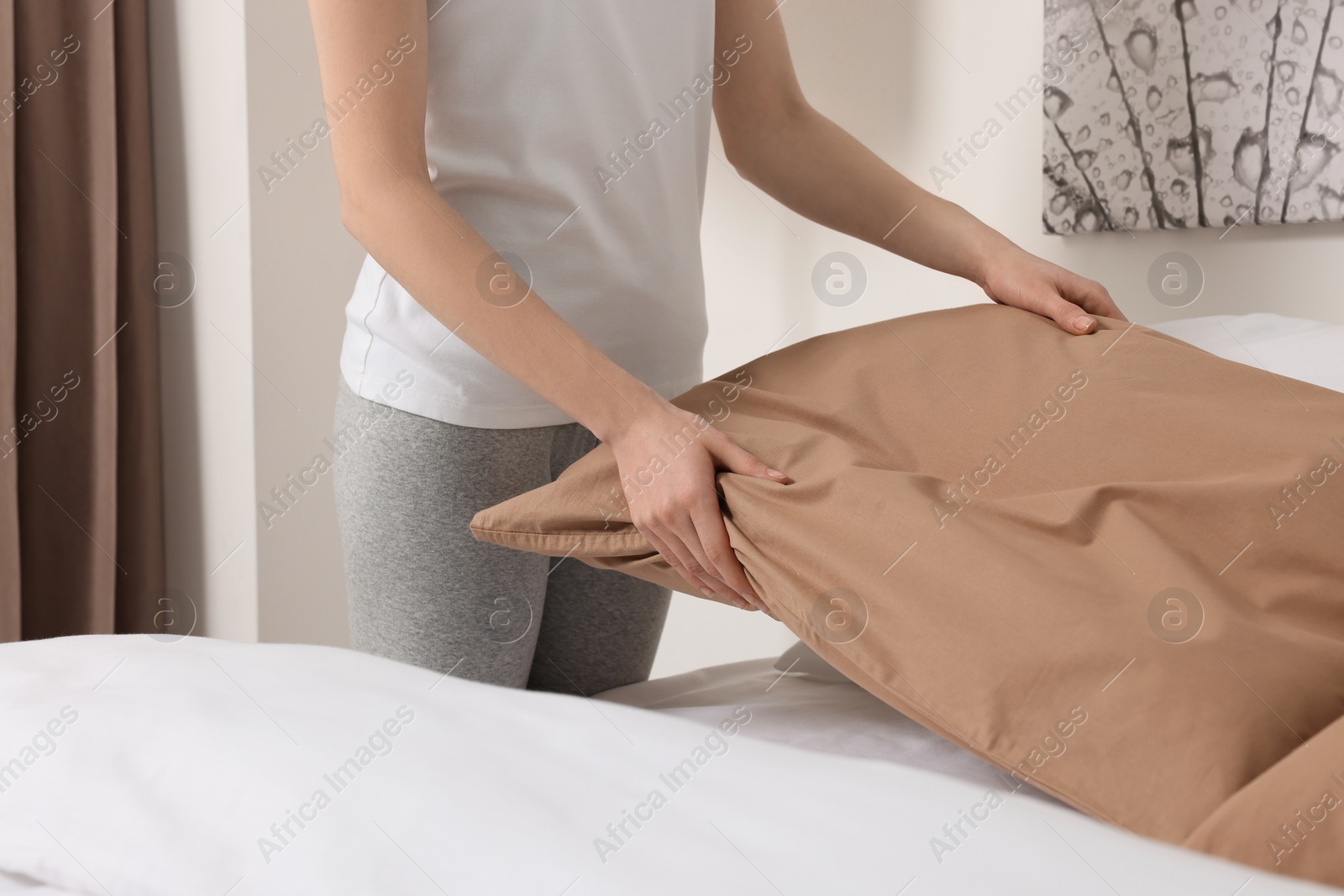 Photo of Young woman making bed in room, closeup