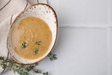 Photo of Delicious turkey gravy and thyme on white tiled table, top view. Space for text