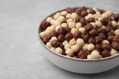 Photo of Tasty cereal balls in bowl on grey table, closeup. Space for text