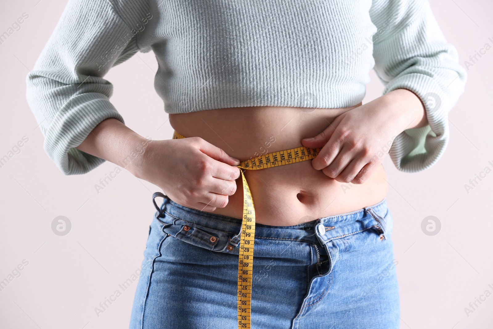 Photo of Woman with measuring tape on white background, closeup. Overweight problem after New Year party