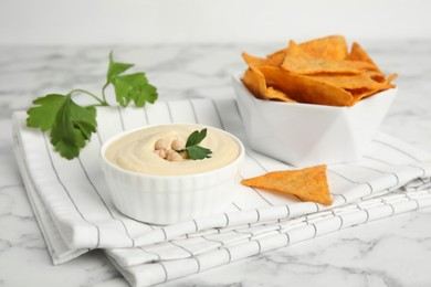 Photo of Delicious hummus with nachos on white marble table