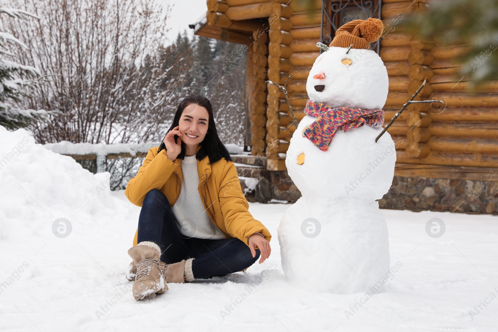 Photo of Young woman near funny snowman outdoors. Winter vacation