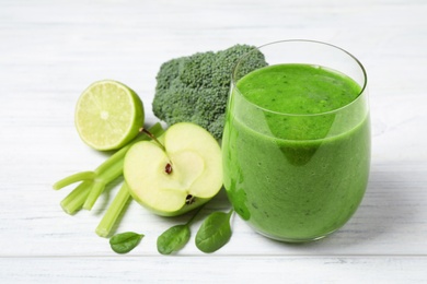 Delicious green juice and fresh ingredients on white wooden table