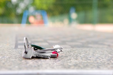 Photo of Keys forgotten on grey stone table outdoors. Space for text. Lost and found