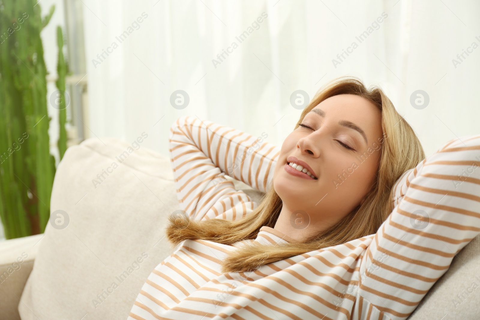 Photo of Beautiful young woman relaxing on sofa at home, space for text