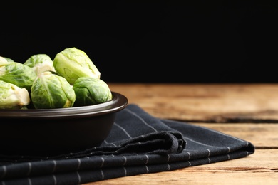 Bowl with fresh Brussels sprouts on wooden table, closeup. Space for text