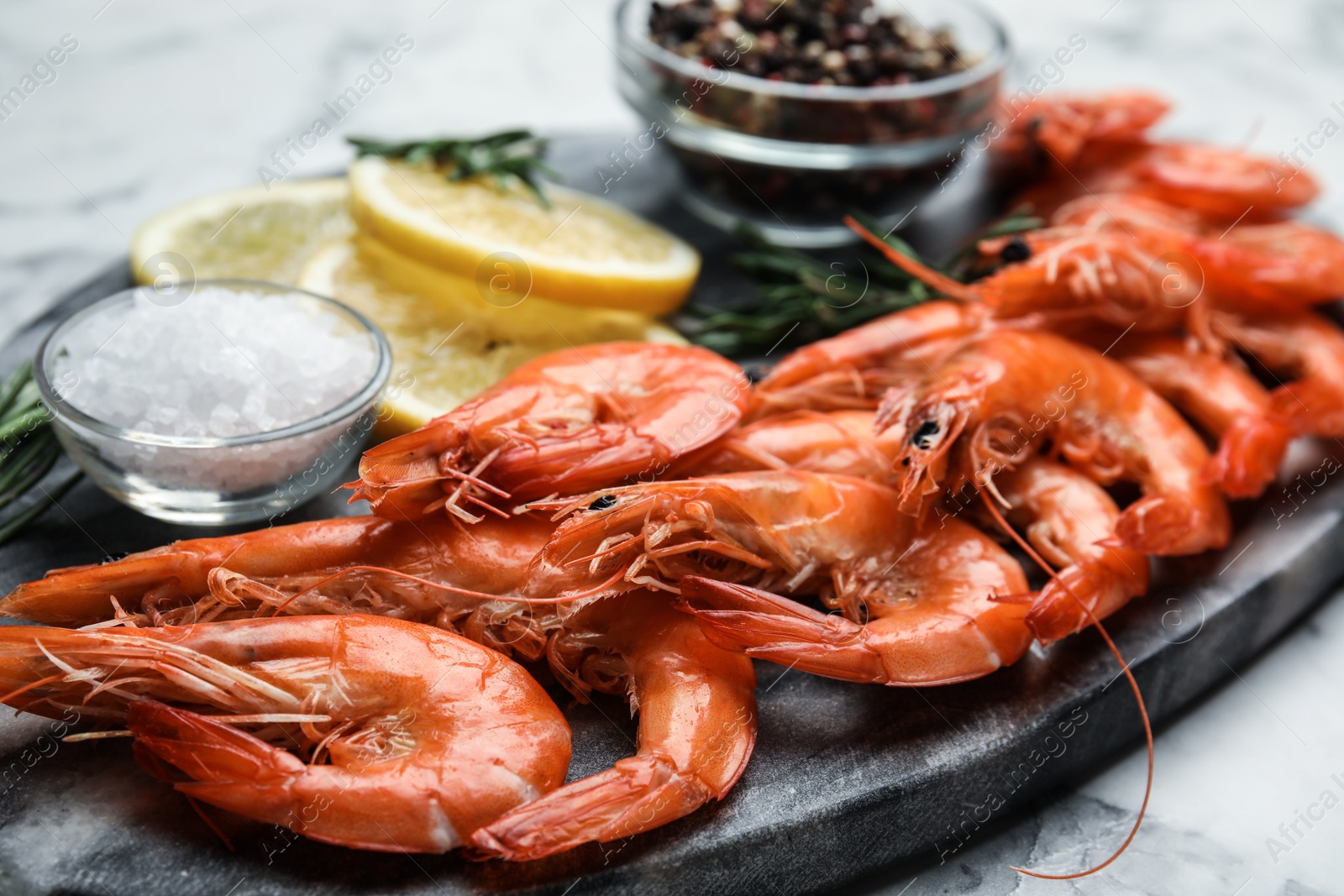 Photo of Delicious cooked shrimps and salt on board, closeup