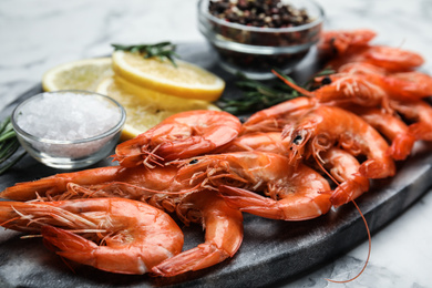 Delicious cooked shrimps and salt on board, closeup