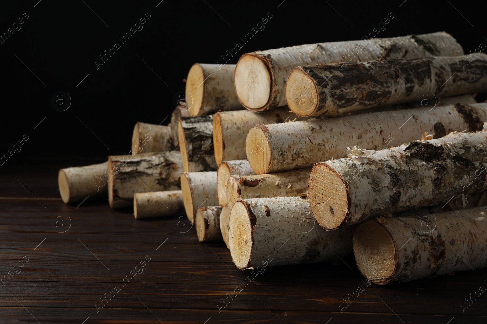 Photo of Cut firewood on table against black background