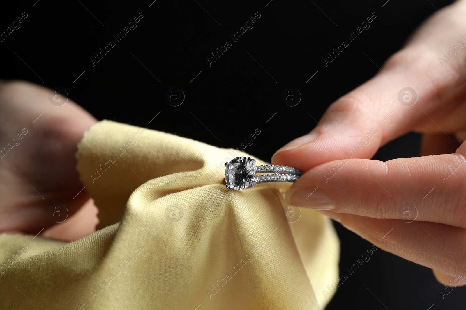 Photo of Jeweler cleaning diamond ring with microfiber cloth, closeup