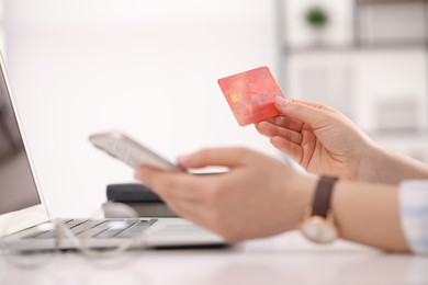 Photo of Woman with credit card using smartphone for online shopping at white table, closeup