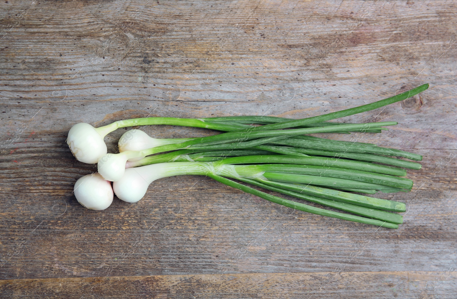 Photo of Fresh green onion on wooden table, top view