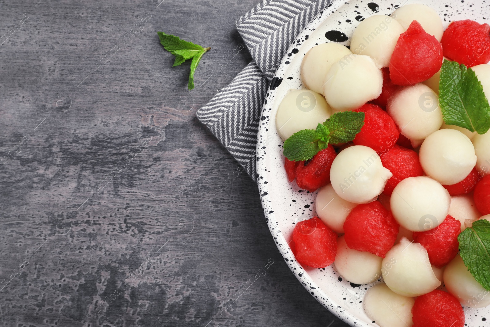 Photo of Plate of melon and watermelon balls on grey background with space for text, top view