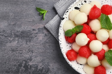 Plate of melon and watermelon balls on grey background with space for text, top view