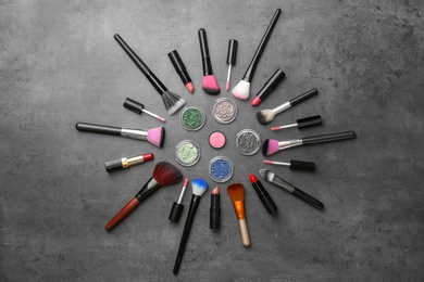 Flat lay composition with cosmetic products and makeup brushes on grey background