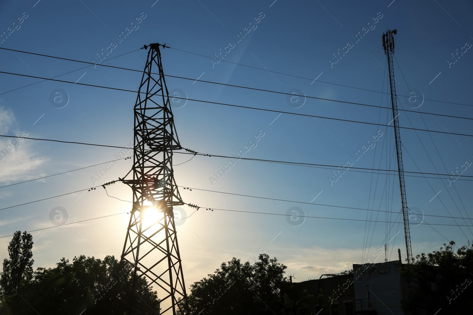 Photo of Silhouettes of high voltage tower and trees in evening