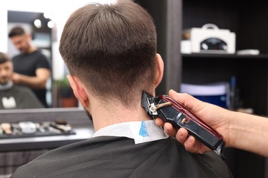 Photo of Professional hairdresser making stylish haircut in barbershop