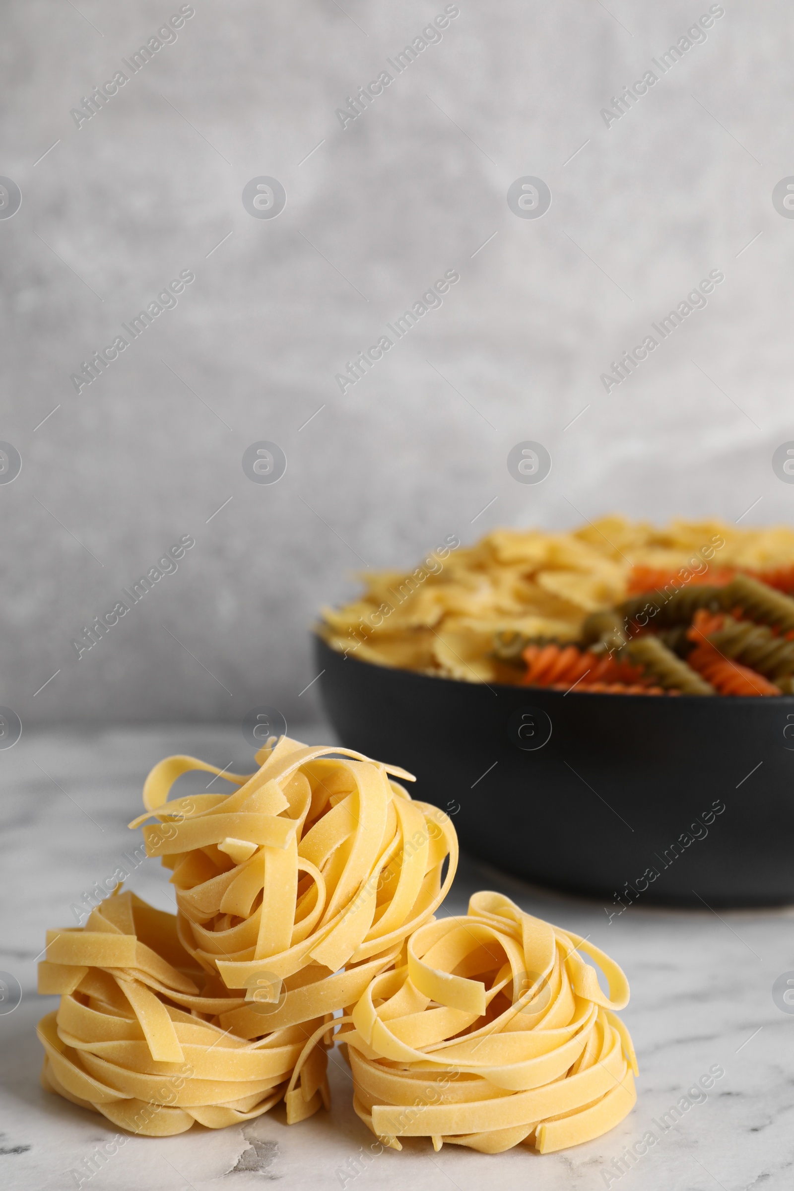 Photo of Uncooked pasta on white marble table. Space for text