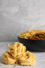 Uncooked pasta on white marble table. Space for text