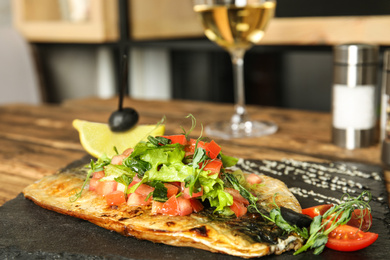 Photo of Delicious grilled fish with vegetables on slate plate, closeup