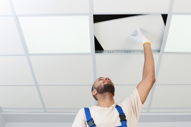 Photo of Electrician repairing ceiling light indoors, low angle view