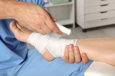 Photo of Doctor applying bandage onto patient's foot in hospital, closeup