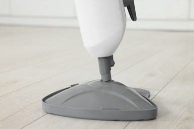 Photo of Cleaning floor with steam mop at home, closeup