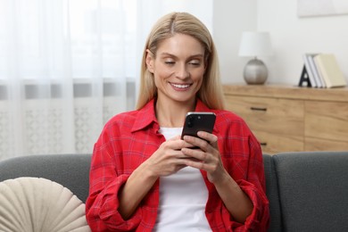 Woman sending message via smartphone at home