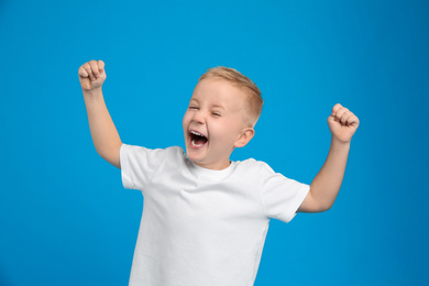 Photo of Portrait of cute little boy on light blue background