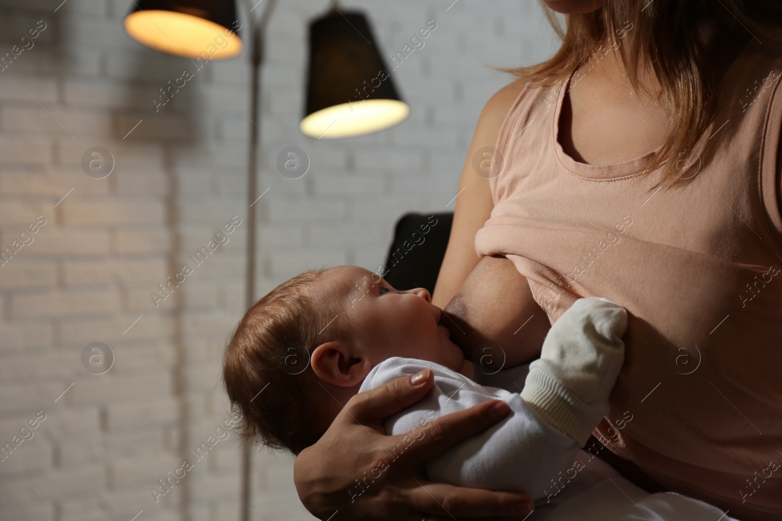 Photo of Young woman breast feeding her little baby at home, closeup