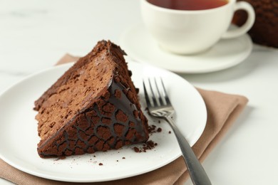Photo of Piece of delicious chocolate truffle cake and fork on white table, closeup