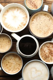Photo of Many cups of different coffees on wooden table, flat lay