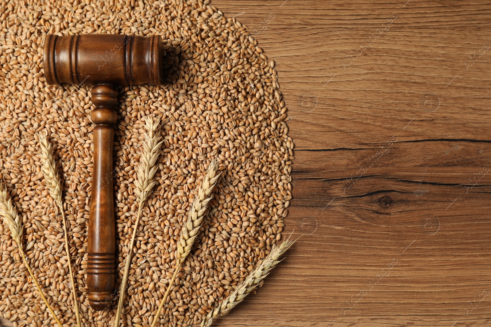 Photo of Agricultural deal. Judge's gavel, wheat ears and grains on wooden table, top view. Space for text