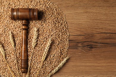 Agricultural deal. Judge's gavel, wheat ears and grains on wooden table, top view. Space for text