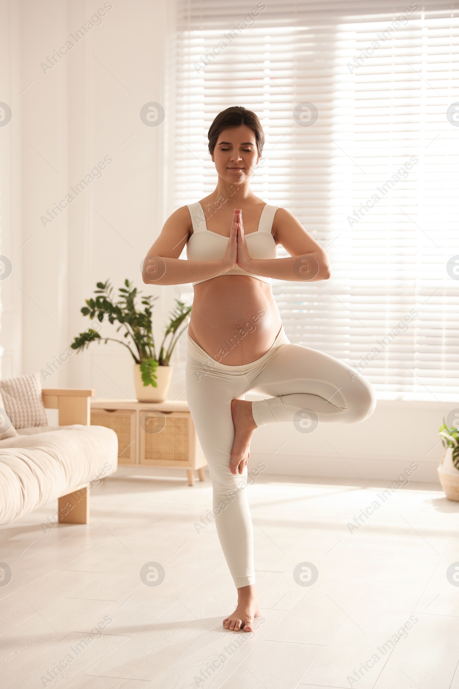 Photo of Young pregnant woman practicing yoga at home