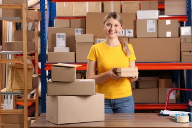 Post office worker with parcels near rack indoors