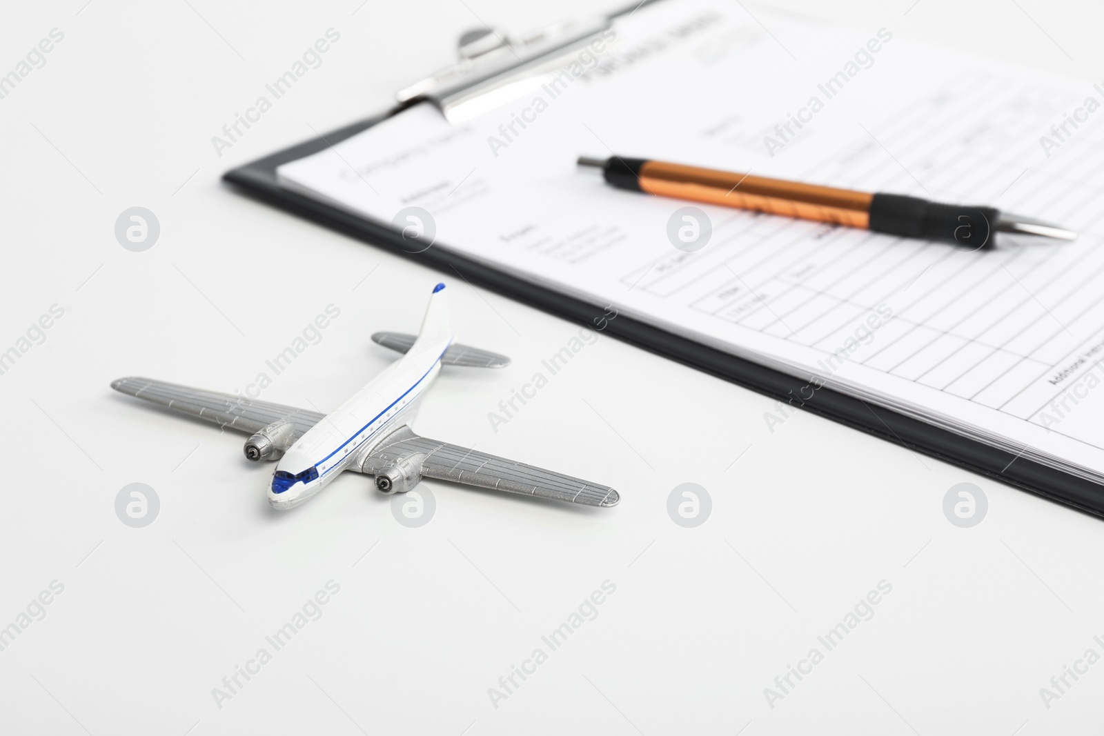 Photo of Toy plane and clipboard with documents on white background. Travel insurance