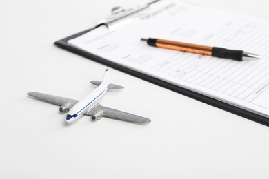 Toy plane and clipboard with documents on white background. Travel insurance