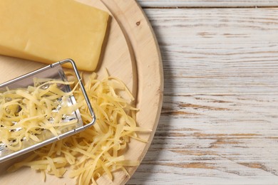 Grated, whole piece of cheese and grater on wooden rustic table, top view. Space for text