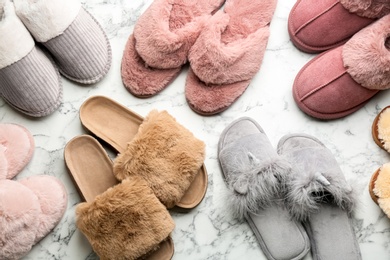 Photo of Many different soft slippers on white marble background, flat lay