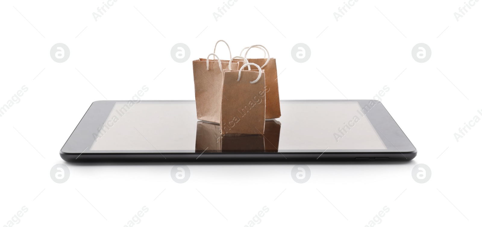 Photo of Internet shopping. Small paper bags and modern tablet on white background