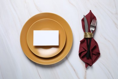 Photo of Beautiful table setting, Plates, napkin, cutlery and empty card on white marble background, flat lay