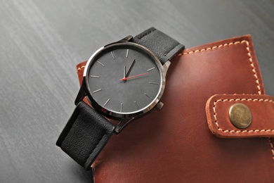 Photo of Stylish wrist watch and wallet on dark background. Fashion accessory